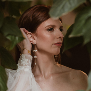 Close-up view of a woman wearing the Jasmine long cascading rice pearl drop earrings with an organic pearl stud.